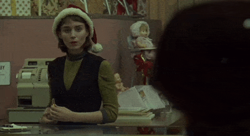 a woman wearing a santa hat stands behind a counter