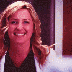 a woman in a white coat and black shirt is smiling