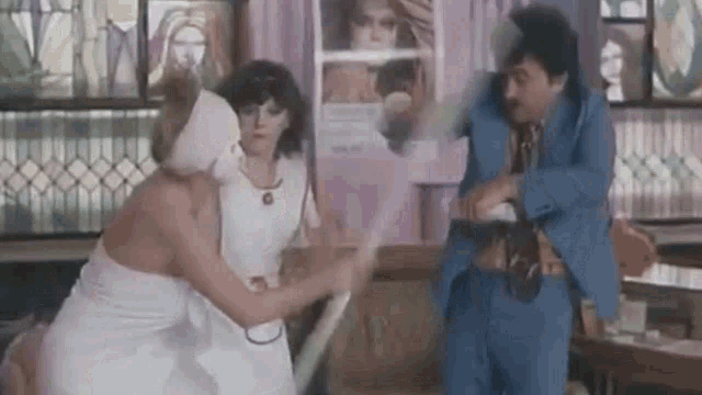 a man in a blue suit is standing next to a woman in a white dress holding a stick .