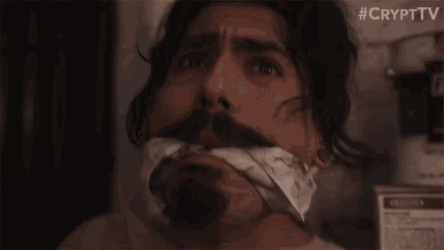 a man with his mouth taped with a bandana has #crypttv written on the bottom of the image