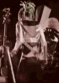 a man is playing a guitar on a stage in a dark room .