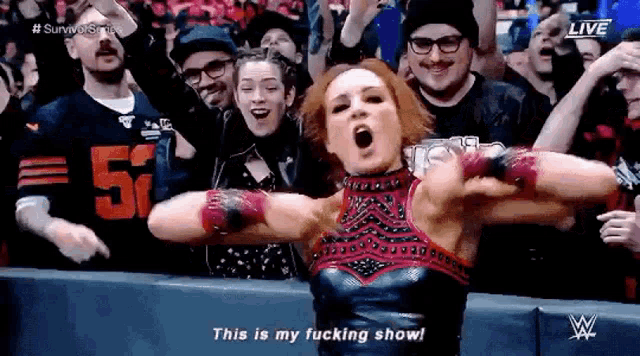 a female wrestler is standing in front of a crowd with her arms outstretched .