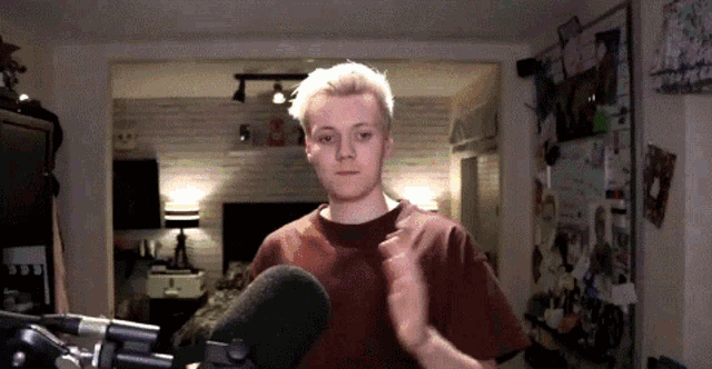 a young man is standing in front of a microphone in a living room