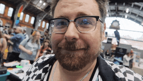 a man with glasses and a beard is smiling
