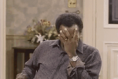 a man is sitting in a chair with his hands on his face .