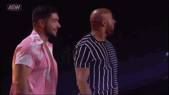 two men are standing next to each other in front of a sign that says all elite wrestling