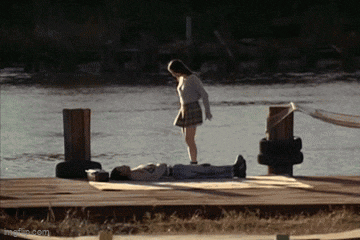 a girl is standing next to a man laying on the ground