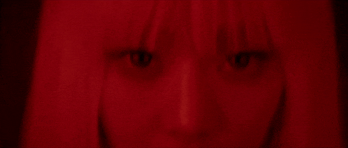 a close up of a woman 's eyes in a dark room with red hair .