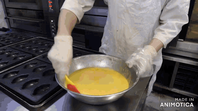 a person is mixing a yellow liquid in a metal bowl with a spatula and the words made in animotica behind them