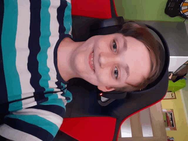 a boy wearing headphones and a striped shirt smiles