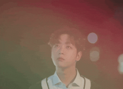 a young man in a white shirt and black sweater is looking up