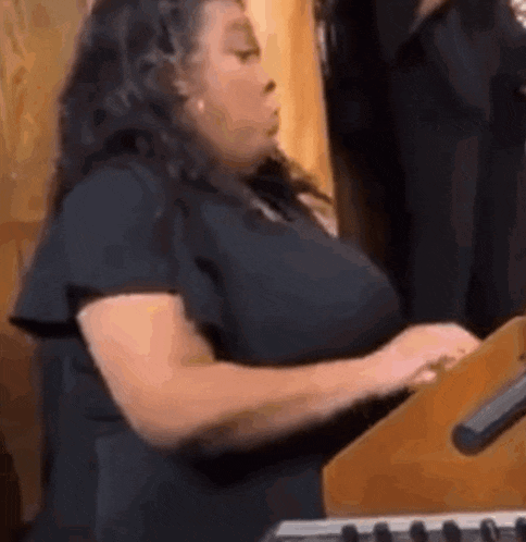 a woman in a black shirt is playing a keyboard .