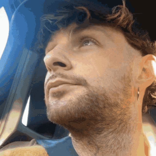 a close up of a man 's face with a beard and earrings