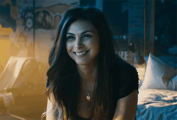 a woman is smiling while sitting on a bed in front of a wall that says maze