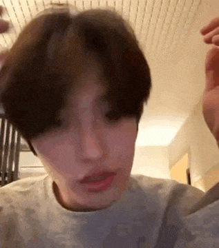 a young man with short hair is taking a selfie in a room with a ceiling fan .