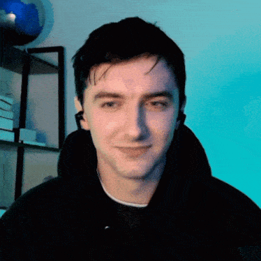 a man wearing headphones looks at the camera with a blue background