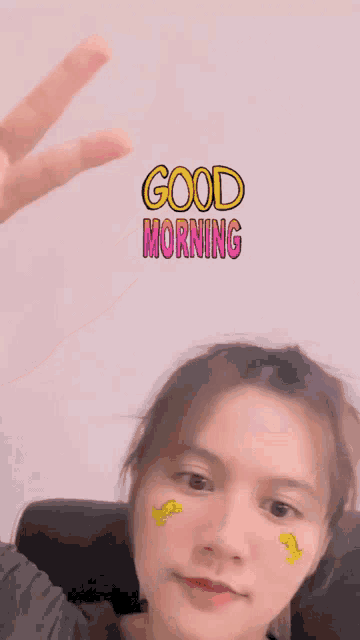 a woman giving a peace sign with the words good morning written on her face