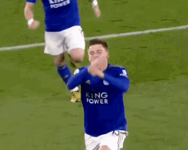 a soccer player wearing a blue king jersey is kneeling on the ground .