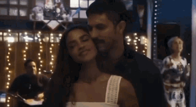 a man and a woman are hugging each other in a room with a lot of lights .