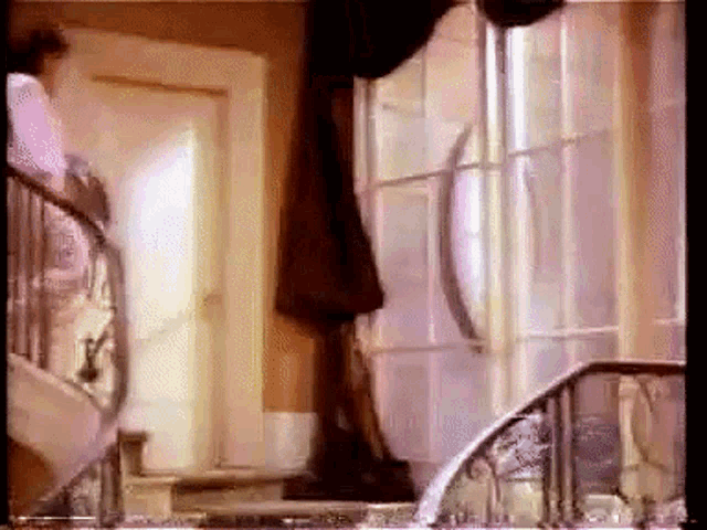 a woman is walking down a set of stairs in a room with a window .