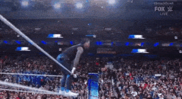 a wrestler is jumping over a rope in front of a crowd at a smackdown event