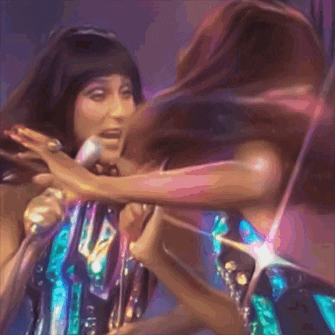 cher is singing into a microphone while another woman holds her hair