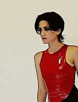 a man in a red tank top is standing in front of a white background .
