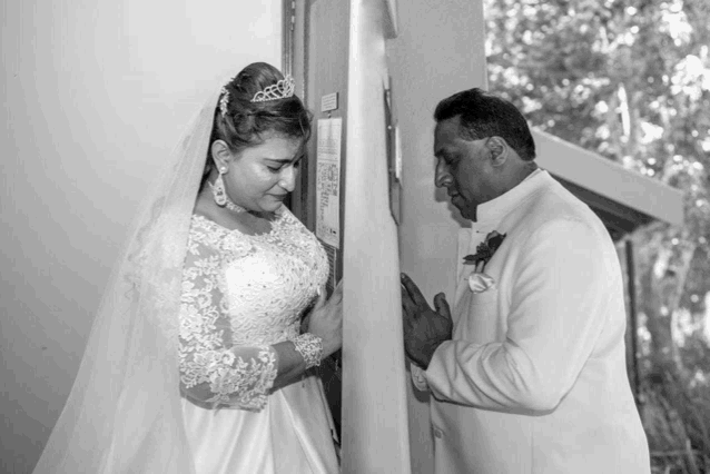 a black and white photo of a bride and groom in front of a door