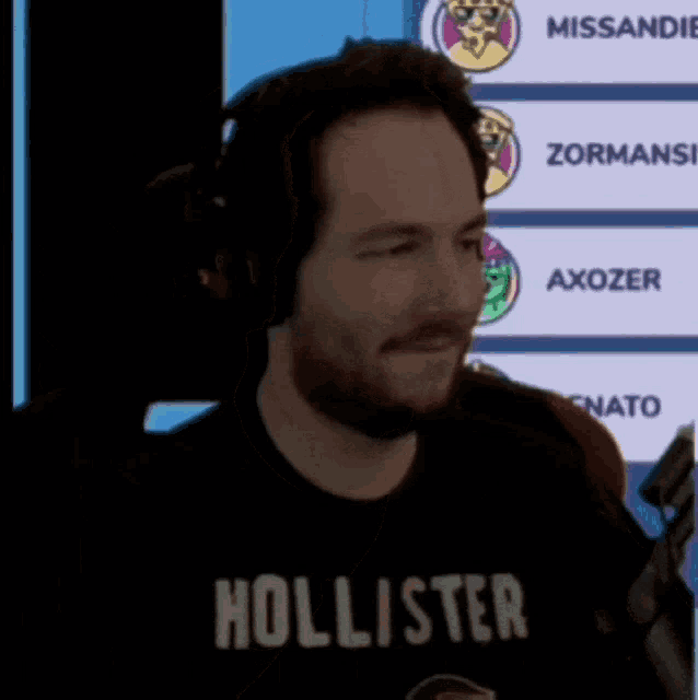 a man wearing a hollister t-shirt is talking into a microphone
