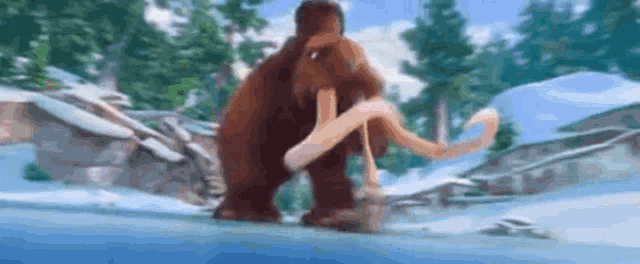 a mammoth is walking through the snow in a snowy forest .
