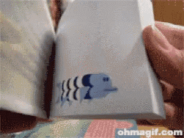 a person is holding a piece of paper with a fish on it and the website ohmagif.com is visible in the corner