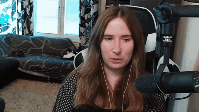 a woman wearing headphones sits in front of a microphone that says ' aerus ' on it