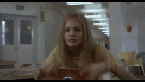a woman in a yellow shirt is sitting in a hallway