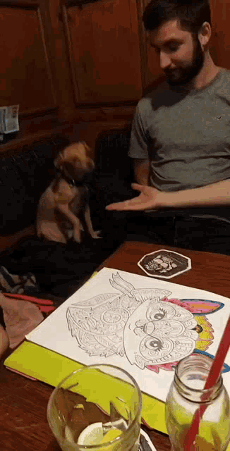 a man is sitting at a table with a drawing of a dog on it