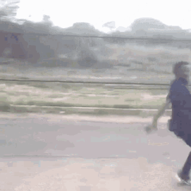 a man in a blue shirt is walking down a road .
