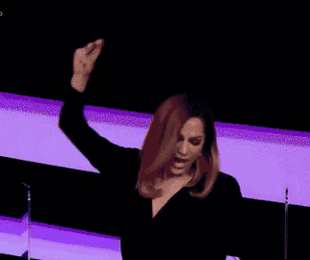 a woman with her arms in the air is wearing a black top