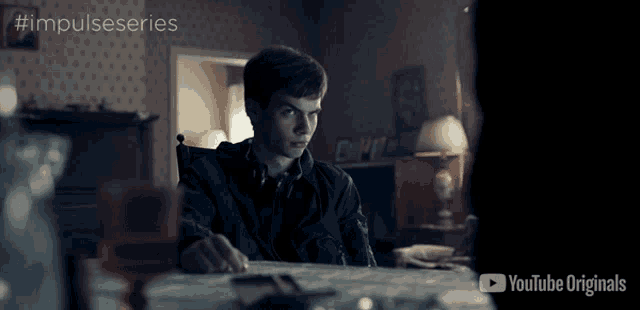 a young man sits at a table with a youtube originals logo