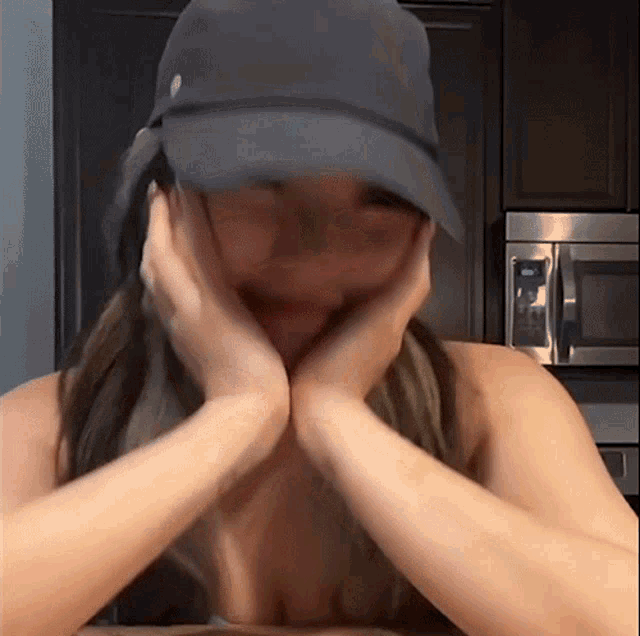 a woman wearing a black hat is covering her mouth with her hands