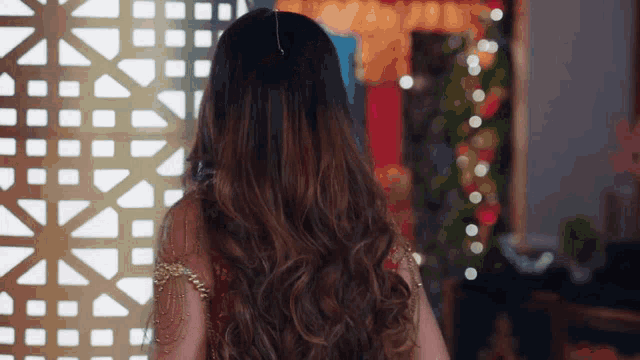a woman with long hair is standing in front of a fence
