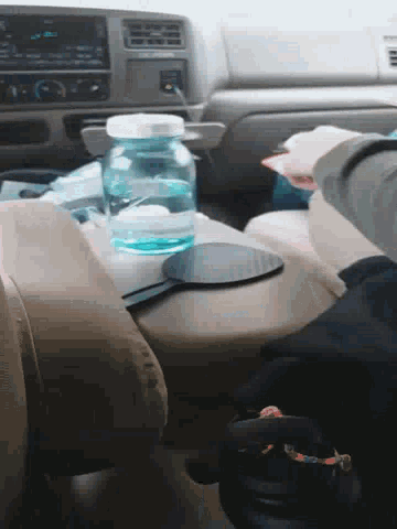 a person sitting in a car with a bottle of water on the arm rest