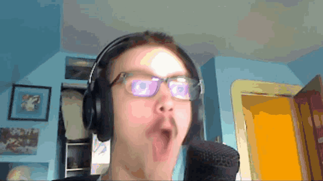 a man wearing headphones and glasses is making a surprised face
