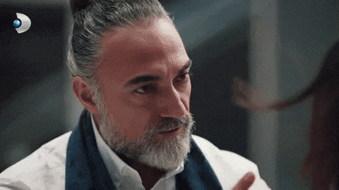a man with a beard wearing a white shirt and a blue scarf