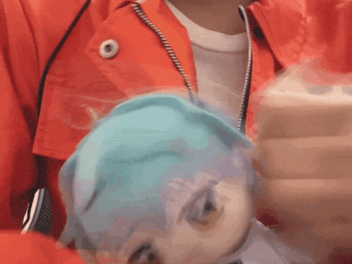 a person wearing a red jacket is holding a blue mask