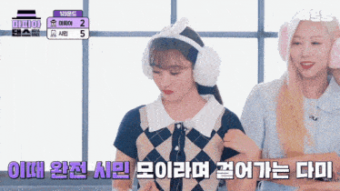 two girls wearing ear muffs are standing next to each other in front of a sign that says ' twice '