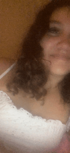 a woman with curly hair is smiling and wearing a white top