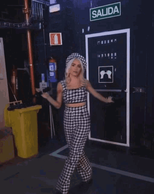 a woman in a plaid top and pants is standing in front of a sign that says salida