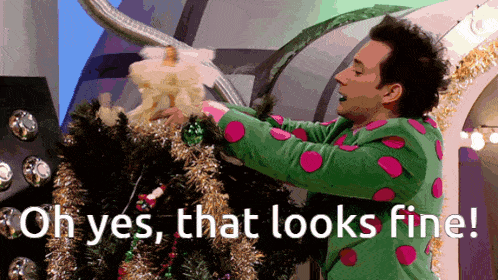 a man in a green and pink polka dot sweater decorates a christmas tree with the words oh yes that looks fine