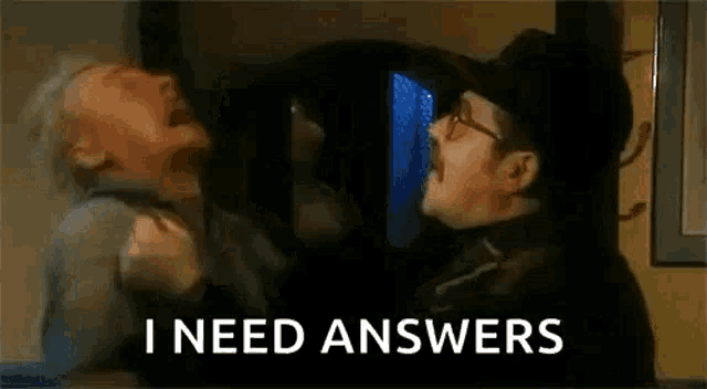 a man is holding another man 's arm and says `` i need answers '' while another man looks on .