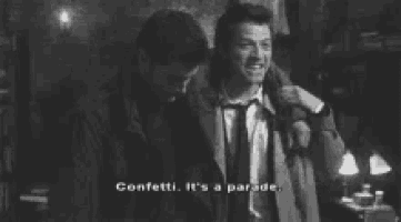 two men are standing next to each other in a dark room and one of them is holding the other 's arm .