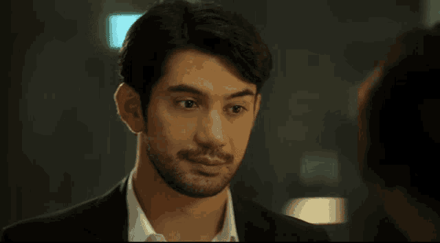 a man with a beard wearing a black suit and white shirt